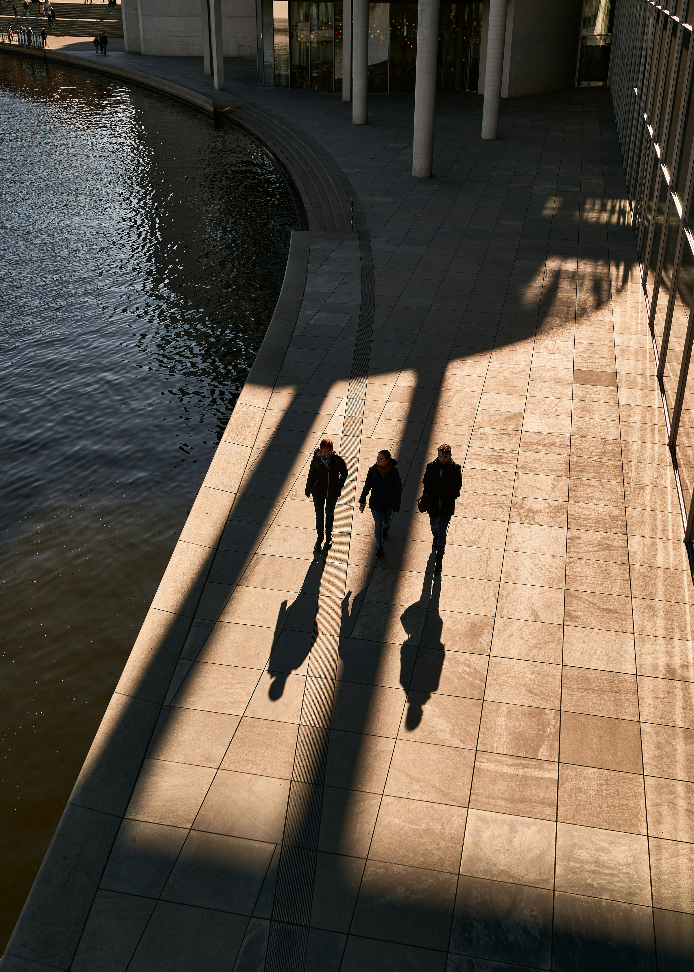Three professionals walking beside a reflecting pool